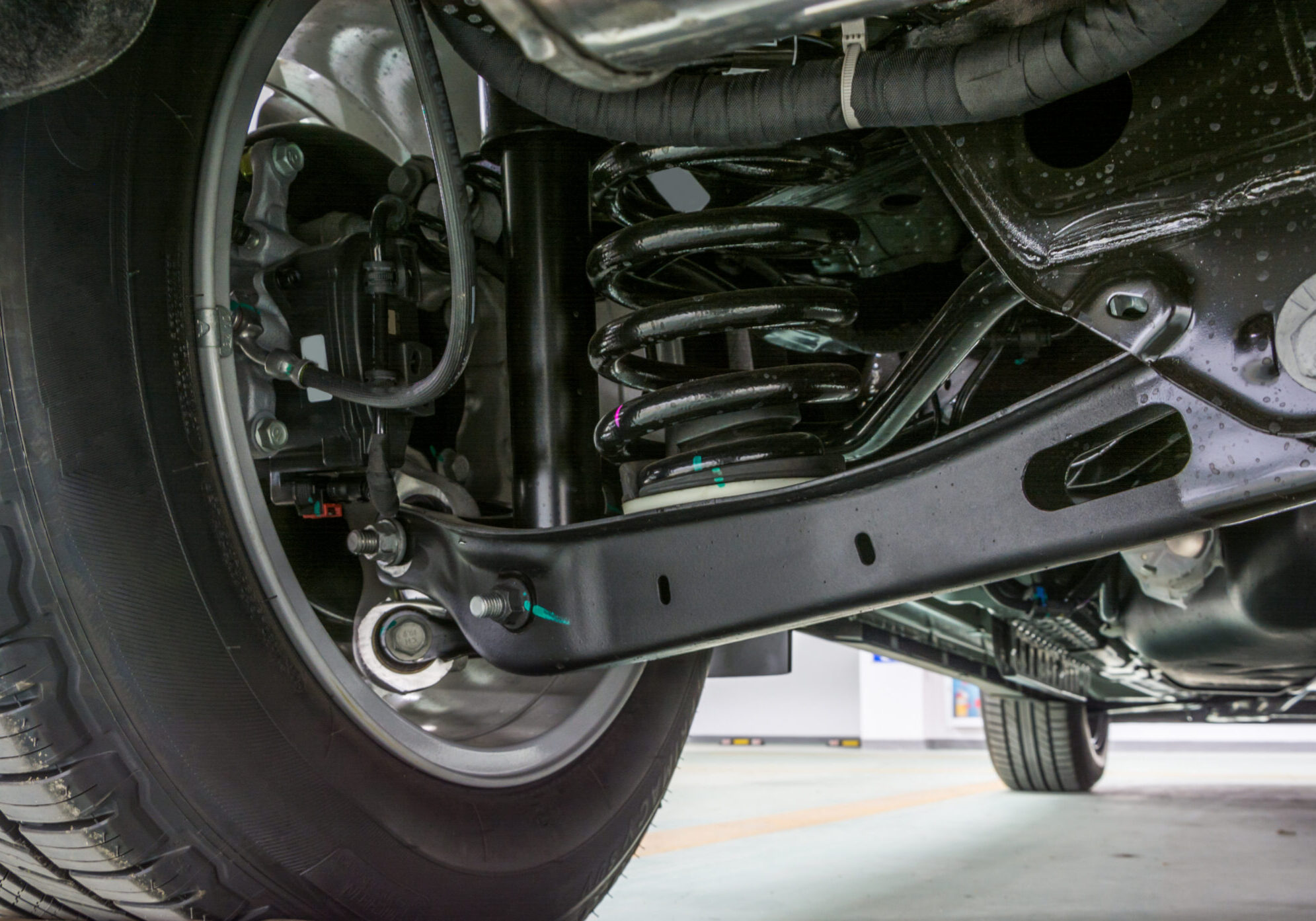 Close-up of a vehicle's suspension system and tire in a workshop setting.