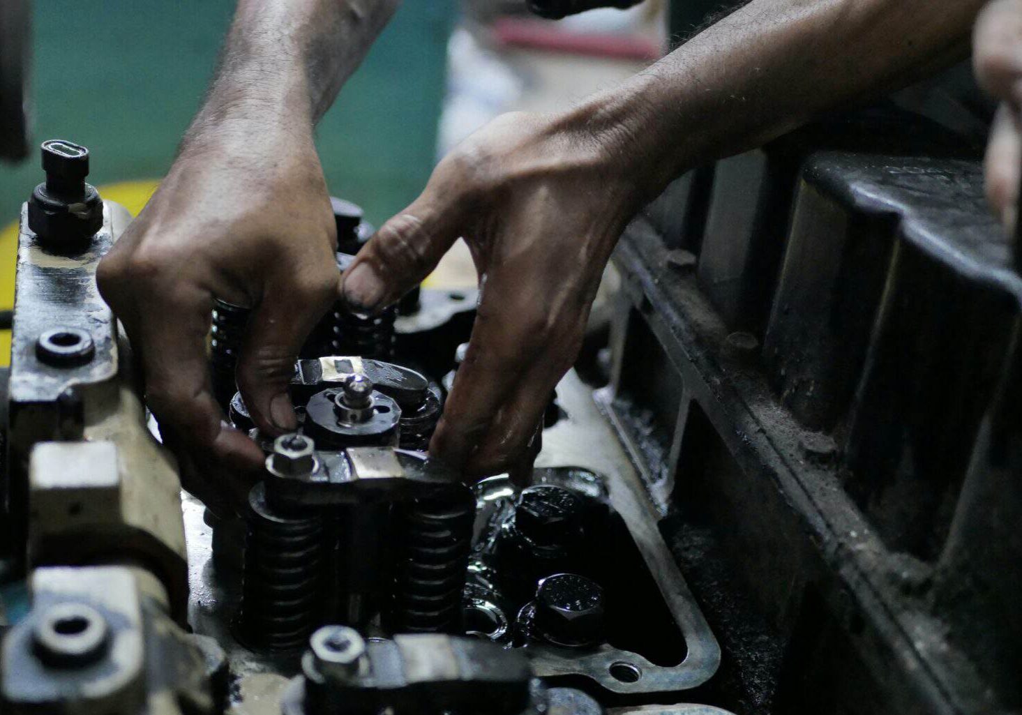 Mechanic working on diesel engine components in a workshop.